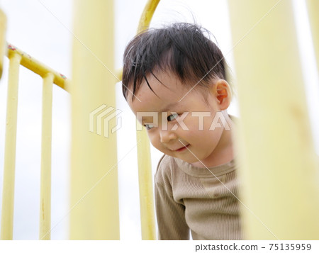 Toddler photographed from between the grids on the slide Toddler photographed from between the grids on the slide 75135959