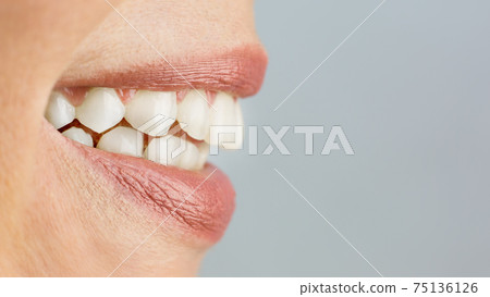 Woman's smile close-up, copy space on gray background 75136126