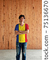 Man wearing Romania flag color shirt and cross one's arm on wooden wall background. 75136670