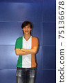 Man wearing Ireland flag pattern shirt and cross one's arm on the blue wall background. 75136678