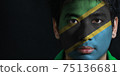 Portrait of a man with the flag of the Tanzania painted on his face on black background 75136681