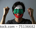 Cheerful portrait of a man with the flag of the Bulgaria painted on his face on grey background. 75136682