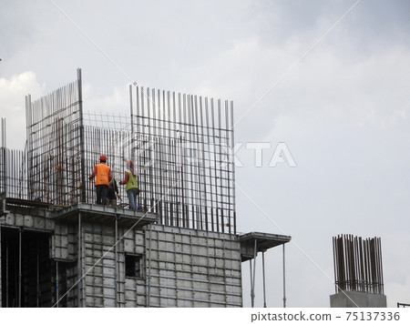 KUALA LUMPUR, MALAYSIA -AUGUST 26, 2017: Construction workers fabricating vertical steel reinforcement bar at the construction site.  75137336