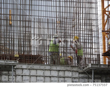 KUALA LUMPUR, MALAYSIA -AUGUST 26, 2017: Construction workers fabricating vertical steel reinforcement bar at the construction site.  75137337