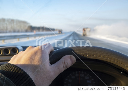 the driver's hand on the steering wheel of the car that is catching up with the truck the driver's hand on the steering wheel of the car that is catching up with the truck 75137443