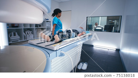 Diverse doctors starting MRI procedure of elderly man 75138018