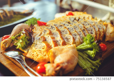 beautiful chicken and mushroom pie with herbs, tomatoes and chicken legs on a wooden board in a restaurant. Selective focus, close-up 75138587