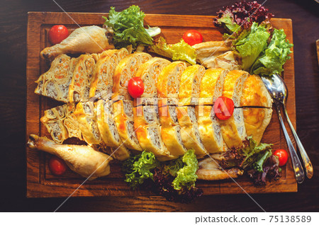 beautiful chicken and mushroom pie with herbs, tomatoes and chicken legs on a wooden board in a restaurant. Selective focus, close-up 75138589
