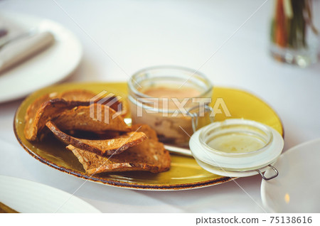 Fresh homemade chicken liver pate in a glass bowl or mold and slices of seed bread with herb and garlic pate on the table. Close-up Fresh homemade chicken liver pate in a glass bowl or mold and slices of seed bread with herb and garlic pate on the table. Close-up 75138616