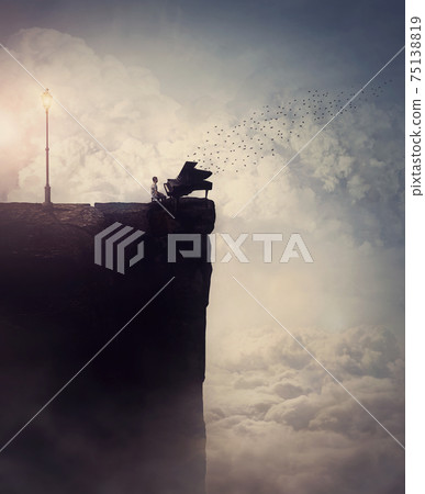 Person silhouette on the edge of a cliff sings and plays a piano song, as flock of birds flying out of the musical instrument. Surreal and inspirational scene above clouds. Adventure and music concept 75138819
