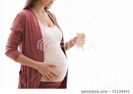 Unrecognizable Pregnant Woman With Glass Of Milk In Hands Standing Near Window Unrecognizable Pregnant Woman With Glass Of Milk In Hands Standing Near Window 75139441