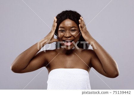 Cheerful Black Woman Standing Wrapped In Towel, Touching Her Beautiful Curly Hair Cheerful Black Woman Standing Wrapped In Towel, Touching Her Beautiful Curly Hair 75139442