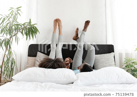 Communication in free time and relaxing on bed, having fun together and lazy at home Communication in free time and relaxing on bed, having fun together and lazy at home 75139478