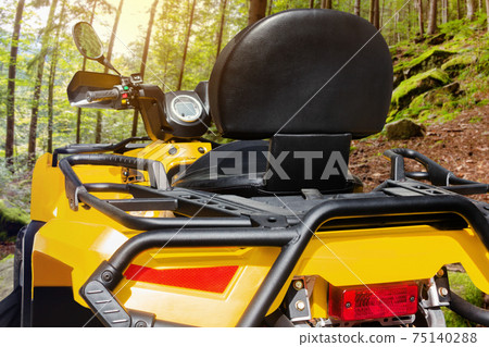 Photo of a yellow offroad touring atv vehicle standing in forest close-up rear view. 75140288