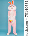 Easter bunny or rabbit or hare with basket of colored eggs, having fun, dancing, celebrates Happy easter. Easter rabbit isolated on blue background 75140631