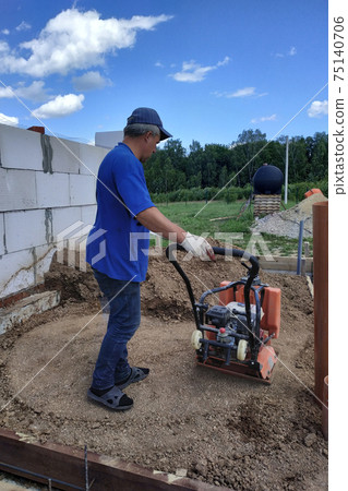 Construction work on the construction site, soil compaction with a vibrating plate, manual equipment. 75140706