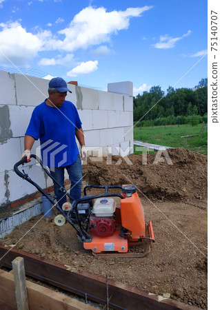 Construction work on the construction site, soil compaction with a vibrating plate, manual equipment. 75140707