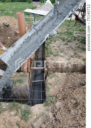 pouring cement into the trench with a mixer, construction work in the summer. pouring cement into the trench with a mixer, construction work in the summer. 75140712