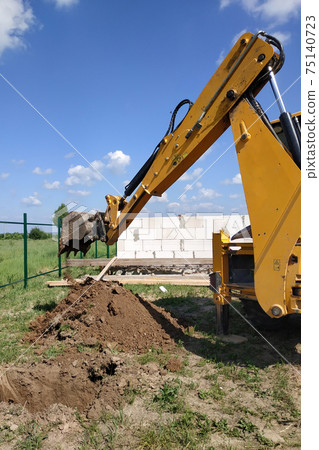 excavator on a construction site digs ditches, the process of work close up. excavator on a construction site digs ditches, the process of work close up. 75140723