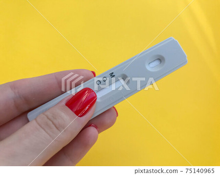 medical procedures. coronavirus test on a bright yellow background. girl with bright red manicure holds a strip. IgG and IgM antibodies test medical procedures. coronavirus test on a bright yellow background. girl with bright red manicure holds a strip. IgG and IgM antibodies test 75140965