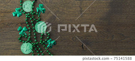 Saint Patrick's day frame with green beads and shamrock on wooden background. 75141588