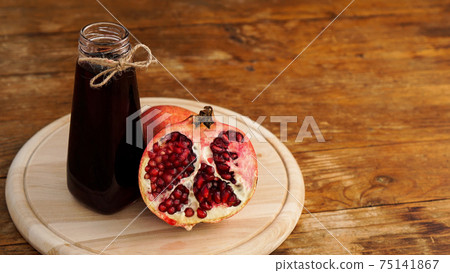 Ripe pomegranates with juice on wooden background. 75141867