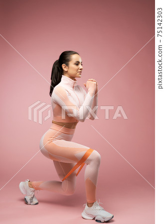 Charming sporty woman doing exercise with resistance band Charming sporty woman doing exercise with resistance band 75142303