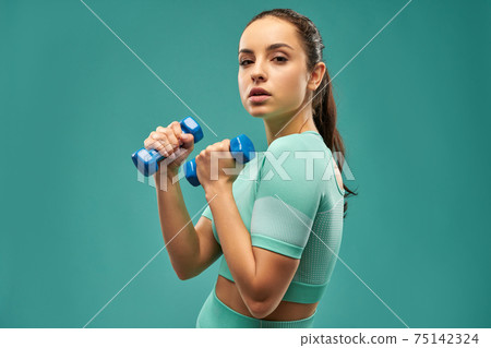 Attractive young woman doing exercise with dumbbells 75142324