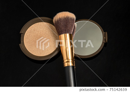 Powder and makeup brush on dark background. Powder with mirror. Soft warm light Powder and makeup brush on dark background. Powder with mirror. Soft warm light 75142639