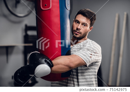 an athlete boxer poses for a photo session in the hall where he is engaged. 75142975