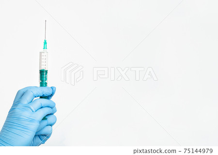 A doctor's hand in a medical glove holds a syringe with a needle to protect against the flu virus A doctor's hand in a medical glove holds a syringe with a needle to protect against the flu virus 75144979