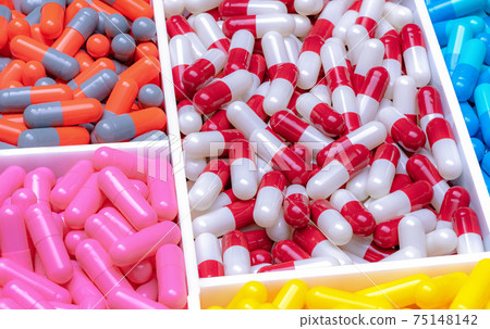 Red-white, orange-gray, pink, blue, and yellow capsules in plastic tray. Antibiotic capsule pills. Pharmaceutical industry. Drug of choice for treatment infections. Antimicrobial drugs resistance. 75148142