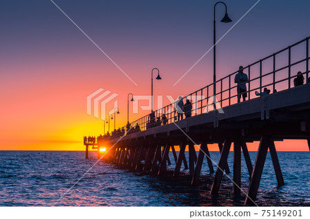 Glenelg Beach beach foreshore with pier and people at sunset 75149201