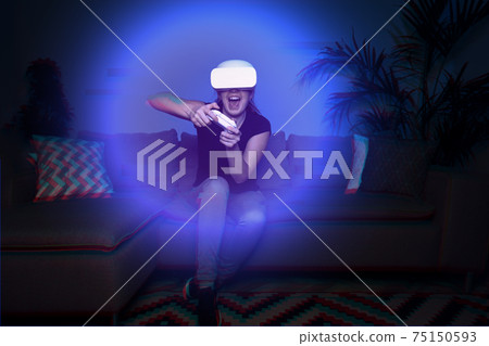 Woman playing game at home using vr headset Woman playing game at home using vr headset 75150593