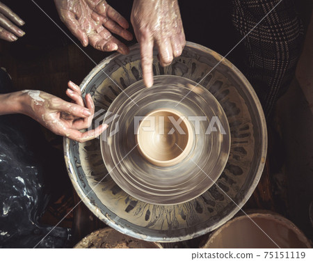 Hands of the master potter and vase of clay on the potter's wheel 75151119