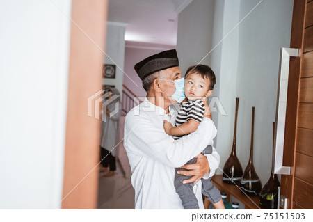 grandparent kissing his granchild at home during visit celebrating eid mubarak 75151503