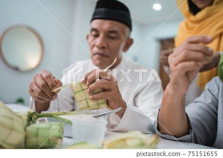 senior muslim couple and daughter making ketupat for eid fitr mubarak 75151655