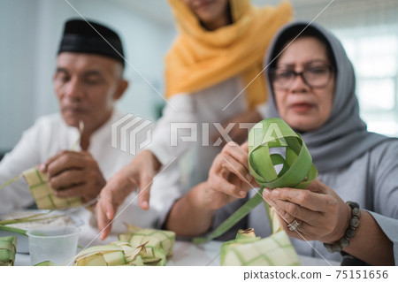 senior muslim couple and daughter making ketupat for eid fitr mubarak senior muslim couple and daughter making ketupat for eid fitr mubarak 75151656