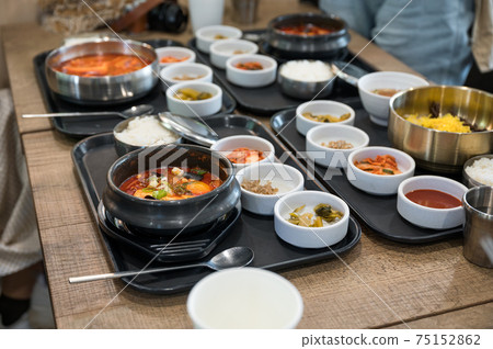 Various of Korean food with spicy soup, kimchi, noodles and vegetable pickle on tray 75152862