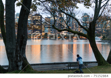 Tourist man take a photo with port of vancouver and illuminated building at Stanley Park Tourist man take a photo with port of vancouver and illuminated building at Stanley Park 75152864