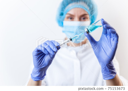 Doctor in gloves filling up syringe from bottle with vaccine, medicine Doctor in gloves filling up syringe from bottle with vaccine, medicine 75153673