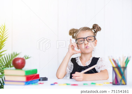 Happy smiling pupil at the desk pointing finger. Girl in the cla 75154161