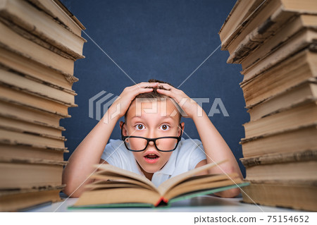 Smart boy in glasses getting crazy of reading book while sitting Smart boy in glasses getting crazy of reading book while sitting 75154652