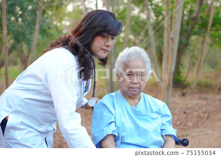 Doctor help and care Asian senior or elderly old lady woman patient sitting on wheelchair at park in nursing hospital ward 75155034
