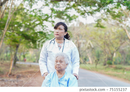 Doctor help and care Asian senior or elderly old lady woman patient sitting on wheelchair at nursing hospital ward 75155237