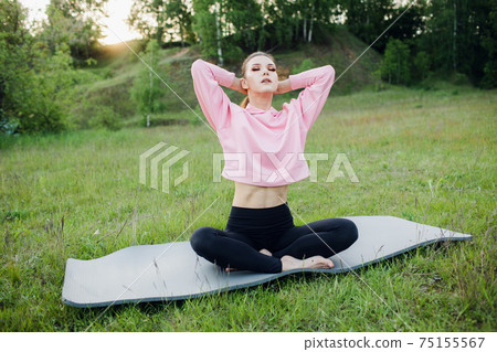 a sporty girl does yoga in the Park. Outdoor sports activities 75155567