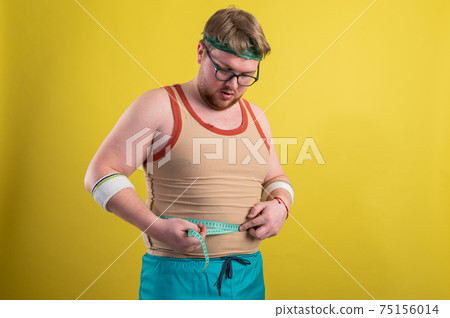 a man in sportswear measures his body volume. Healthy lifestyle concept, healthy food 75156014