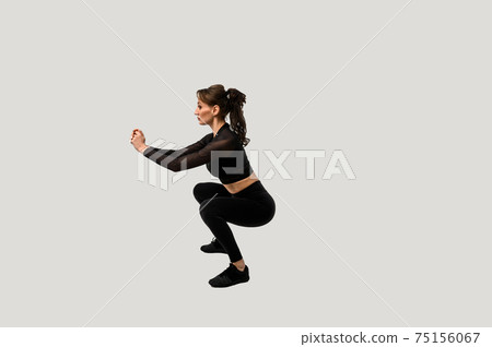 Full length portrait of a young fitness woman doing squatting isolated on a white background 75156067