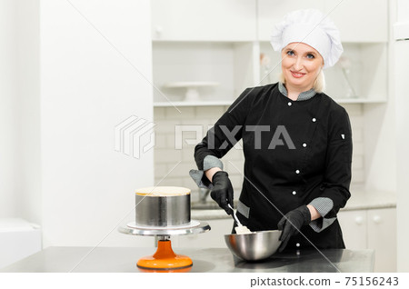 woman pastry chef in uniform prepares cake woman pastry chef in uniform prepares cake 75156243