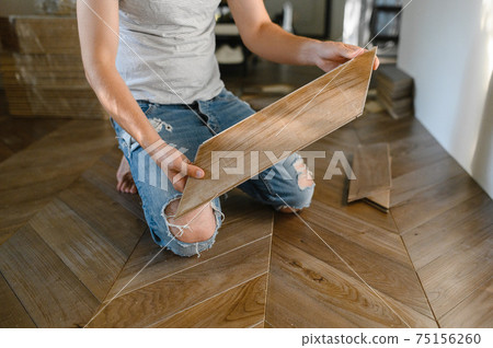 Man laying parquet flooring - closeup on male hands. worker joining parquet floor 75156260